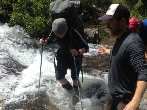 Crossing a mountain stream on summer wilderness adventure